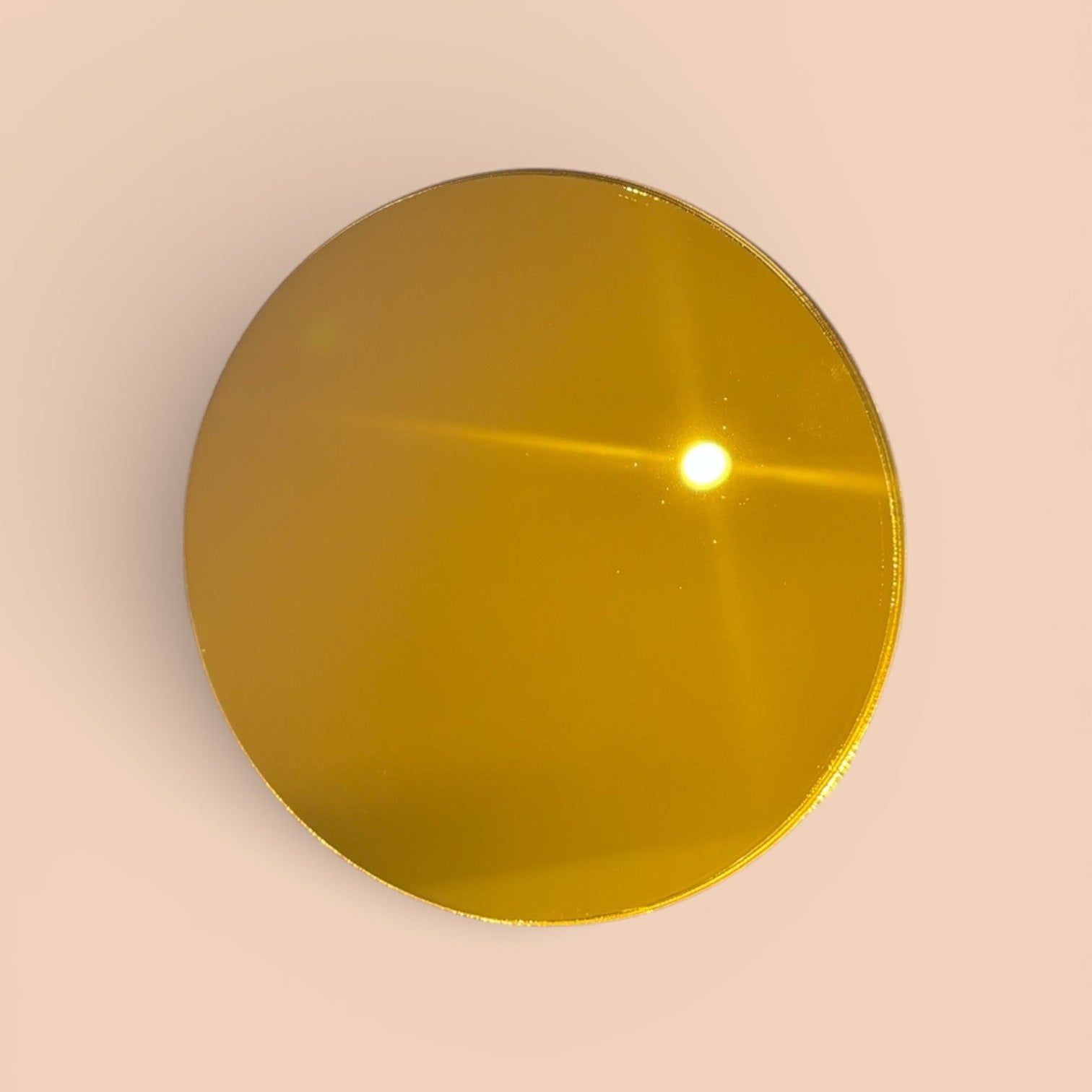 Gold-colored circular acrylic blank on a beige background